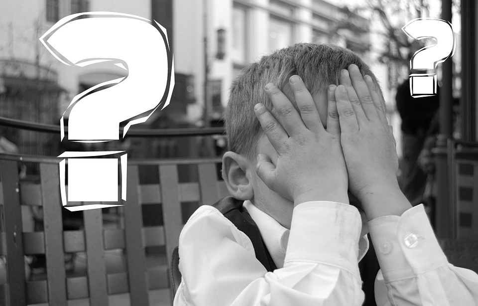 child with hands over his face in embarrassment with a question mark next to him