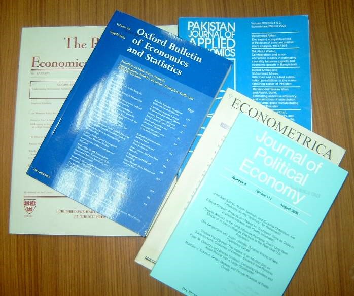 print editions of journals in the economics discipline on a desk stacked on a desk