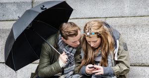 Photo of a teenage girl and guy looking at a cell phone.