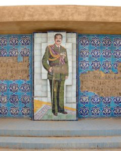 A mosaic of Saddam Hussein and other tile decorations are shown on a wall