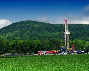 This is a photo of a shale drilling platform below a forested hill