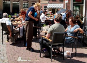 Waitress serves customers in an outdoor cafe.