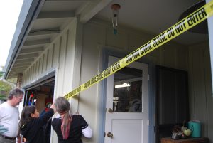 People placing crime scene tape around a house