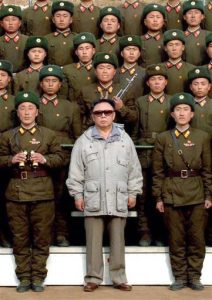 Kim Jong-Il of North Korea is shown wearing sunglasses amid a group of uniformed North Korean soldiers