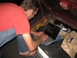 A man leaning over a laptop, typing is pictured here
