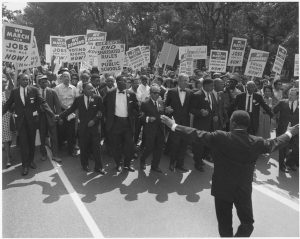 Figure (b) shows a large group of marchers for civil rights