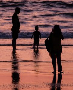 three people at a beach at sunset