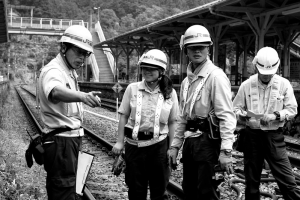 A black and white photograph depicting four railroad maitenance workers. Three of them are male and one is female.