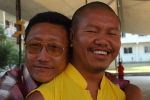 Two men hugging and smiling for the camera.
