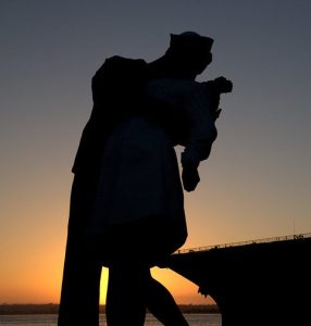 A sunset silouhette of the statue titled "The Kiss" based on the famous photograph.