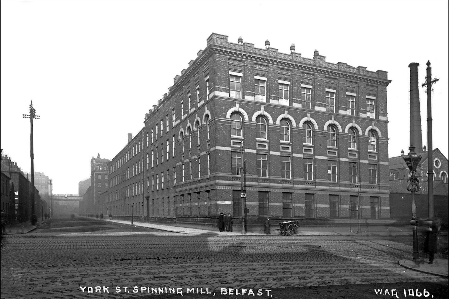 A photograph of ca. 1900 showing the York Street Spinning Mill in Belfast, an imposing brick industrial building of four stories with chimneys and overpasses.