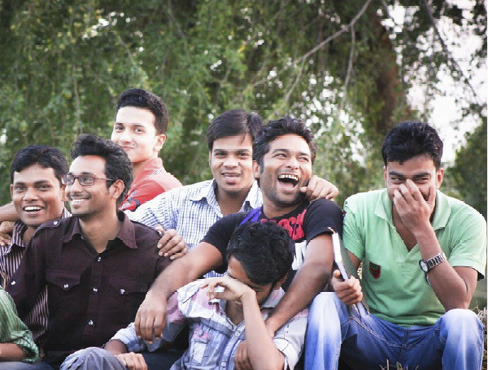 A group of young men sit together laughing and smiling.