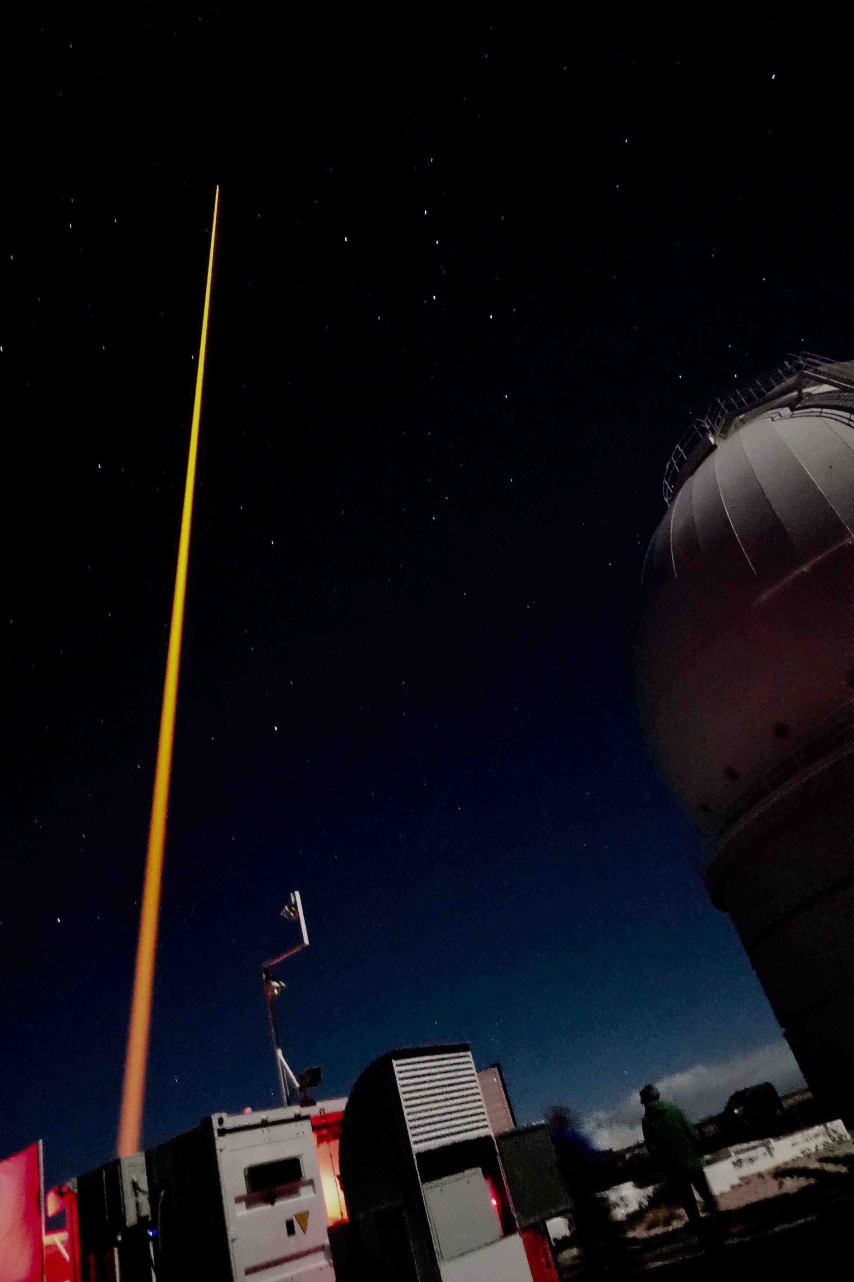 Night sky with orange-gold laser shooting vertically