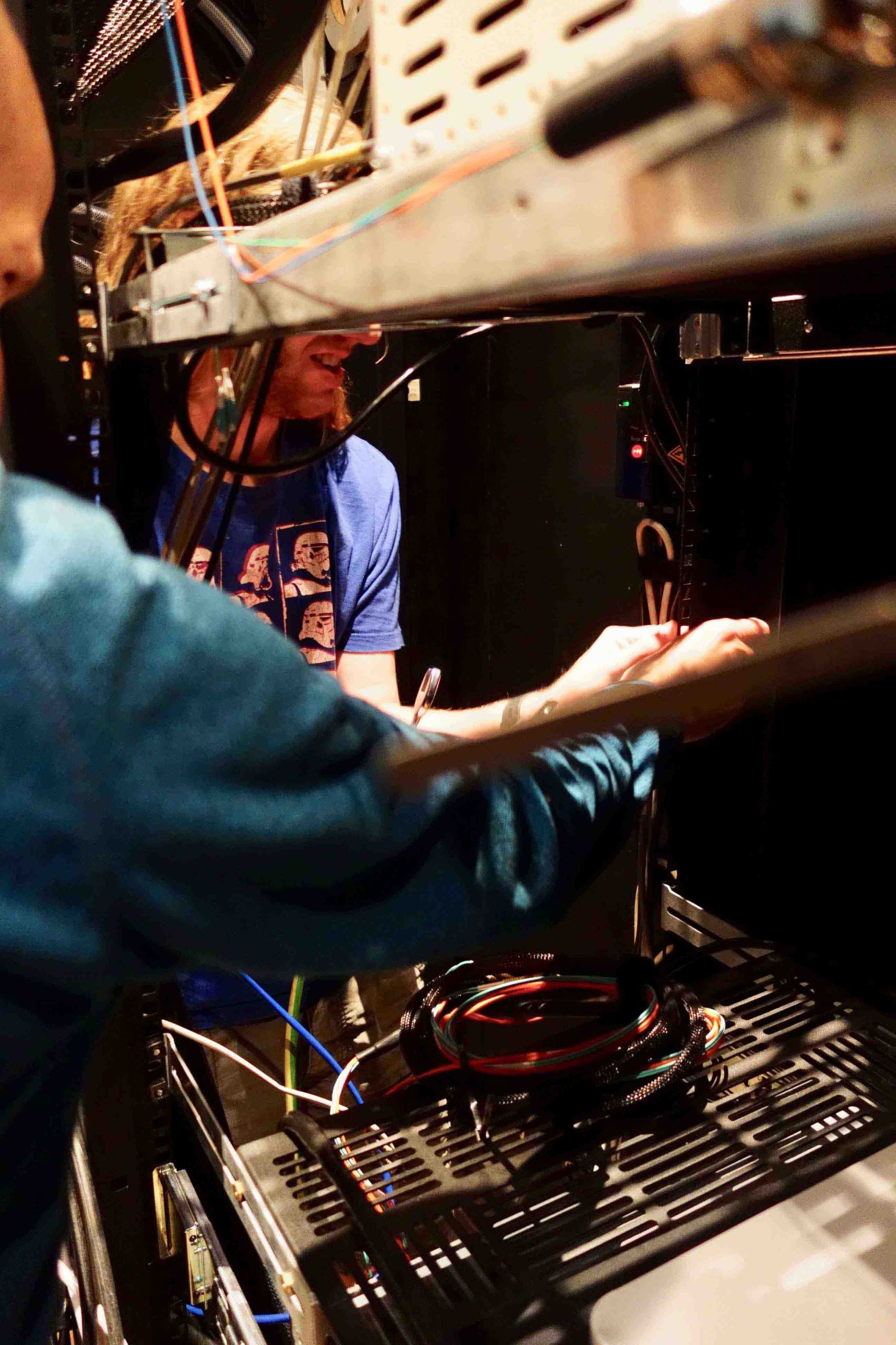 Hands of two people working side by side with wires below