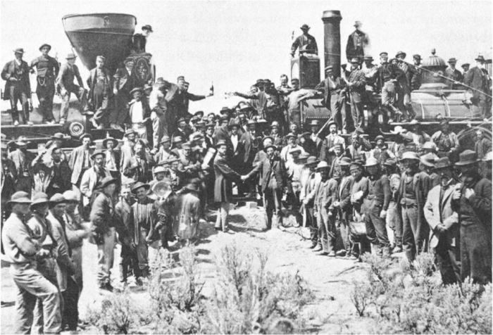 This is a picture of people gathered around the connection of the Pacific Railroad Company and Union Pacific Railroad Company's tracks.