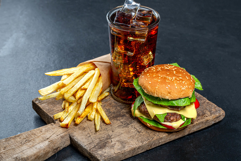 Photo of a large hamburger, French fries, and a soda