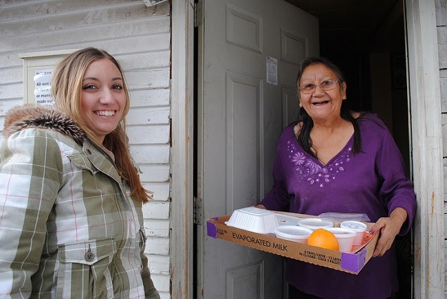 Young woman delivering a meal to a senior.