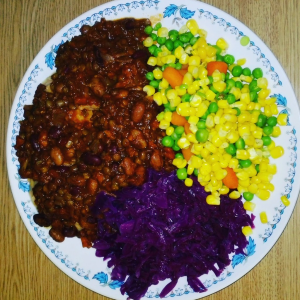 a colorful plate of corn, peas, carrots, purple cabbage, and beans