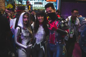Three comic convention attendees dressed as characters from Spider-Man.