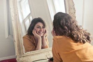 A photo of a woman looking into a mirror.