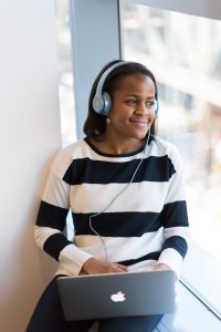 A woman listens to music on her headphones as she uses her computer.