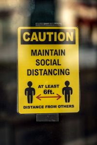 A sign that depicts two figures six feet apart, reading, Caution: Maintain Social Distancing