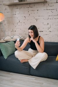 A woman sits on a couch, using FaceTime to talk to a friend.
