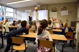 A student raises her hand to get the attention of her teacher.