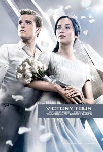 Peeta and Katniss, holding white roses, together in white garments on their victory tour.