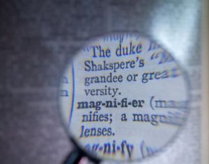 Magnifying glass magnifying the word mag-ni-fi-er