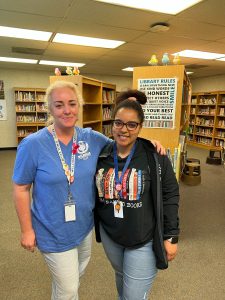 Melissa Englehart standing in the library with her colleague.