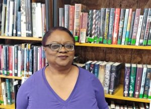 LaDonna Hankins-Ramirez standing in front of book shelves.